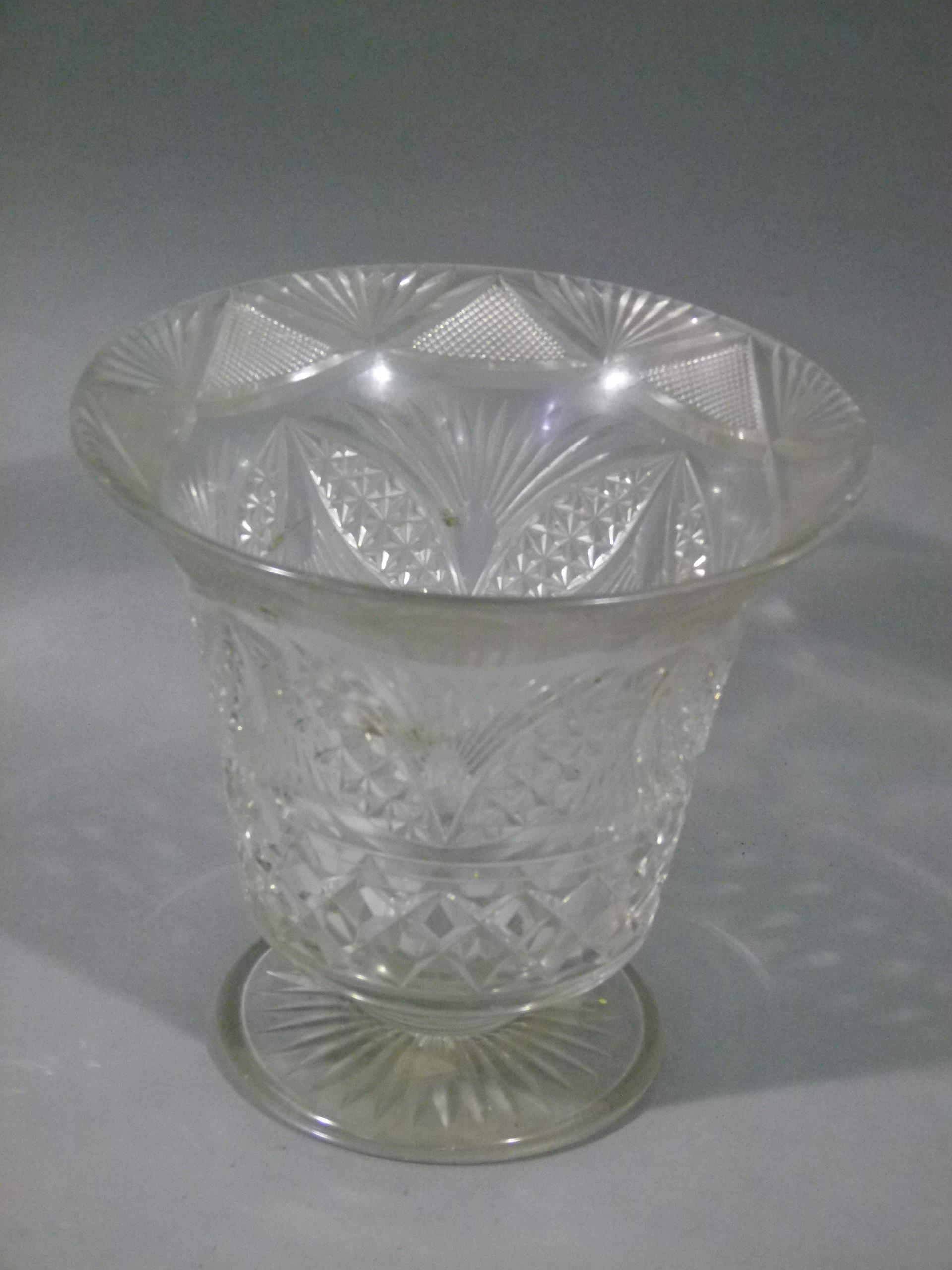 A large cut glass flower vase with flared rim and on short pedestal