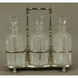 A late Victorian/Edwardian VII silver plated triple decanter stand and three diamond cut glass