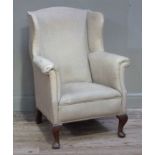 A wing back upholstered armchair on cabriole legs and pad feet