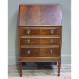 A mahogany veneered small bureau, the butterfly figured flap above three conforming drawers on