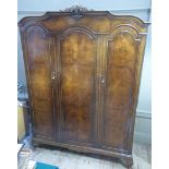 A walnut three door wardrobe with shell cresting and on short cabriole legs