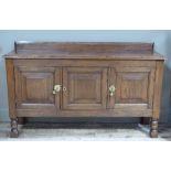 An oak sideboard with shallow back, three panelled fielded panelled doors on turned and block