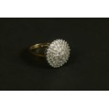 A diamond cluster ring in 9ct gold, the eight cut stones rasped against a circular outline, total