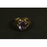 An amethyst dress ring in 9ct gold, the oval faceted stone claw set and raised against textured