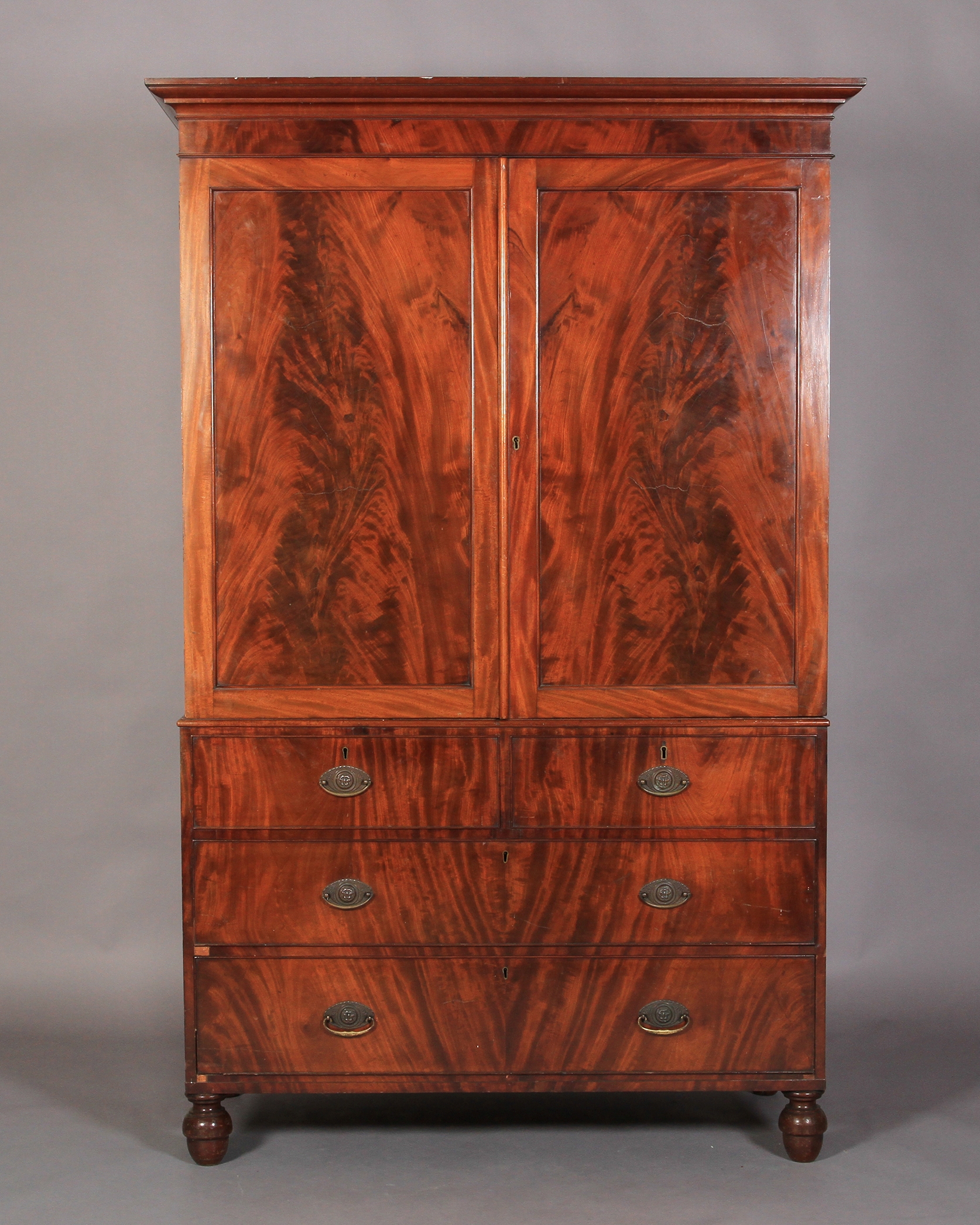 A George IV mahogany clothes press with flared moulded cornice over pair of figure doors enclosing