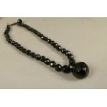 A Victorian jet necklace, the circular faceted beads hung to the centre with a matching slightly