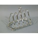 A George V silver four division toast rack of arched ogee form on four compressed bun feet, ring