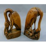 Two wood carvings of a long necked bird clutching a mouse in its feet and a snake in its mouth and