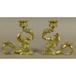 A pair of Victorian brass candlesticks in the form of a dragon holding the sconce in its mouth,