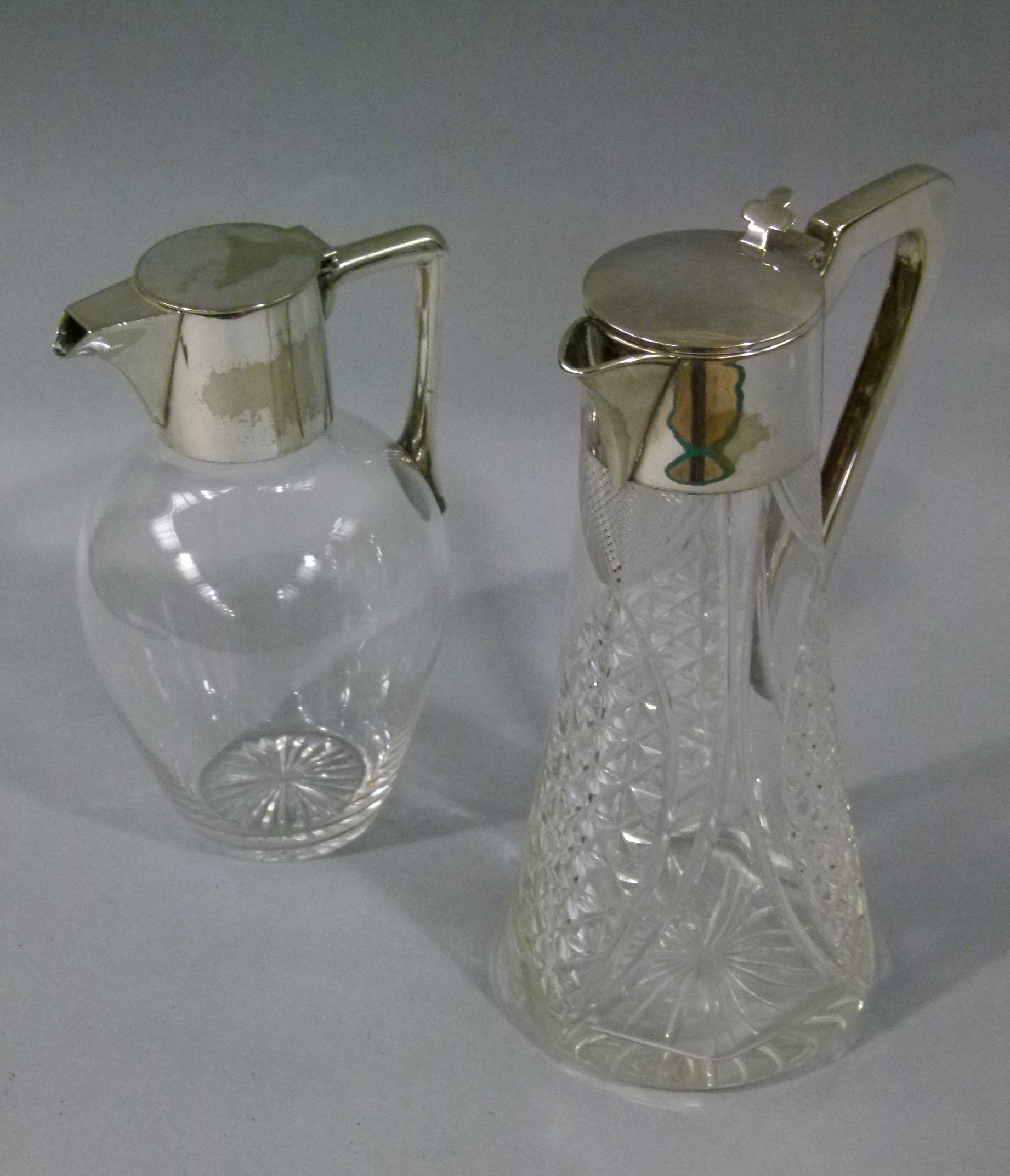 A silver plate mounted and clear glass claret jug with cut base and disc lid; together with