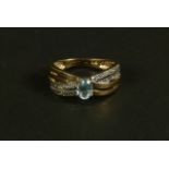 A blue topaz and diamond ring in 9ct gold, claw set to the centre with an oval faceted blue topaz