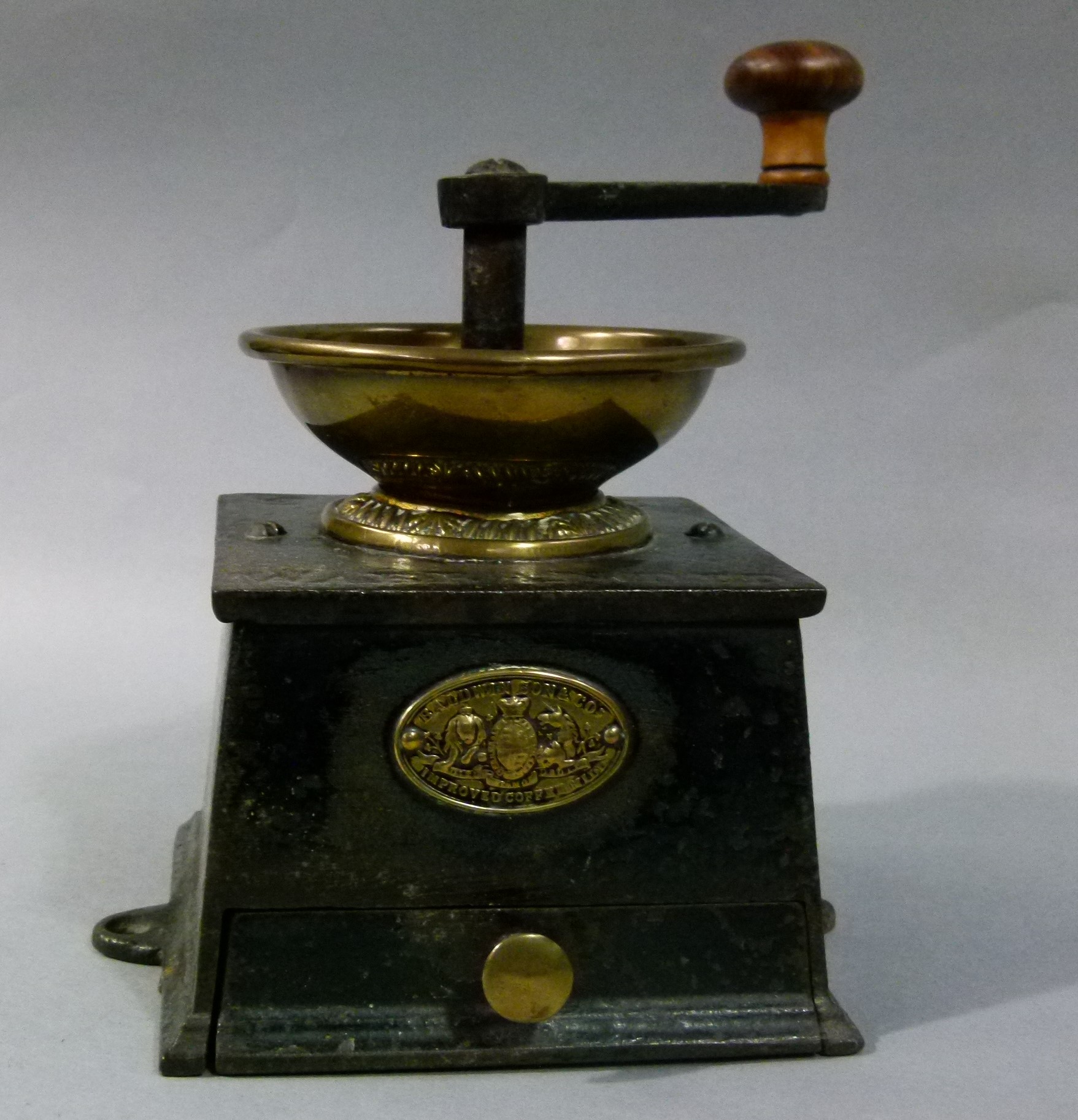 A 19th century brass mounted black lacquered iron coffee mill by Baldwin Son & Co