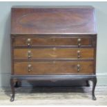 A reproduction mahogany bureau in George III style, the fall-flap with figured oval above three