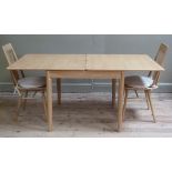 A modern Ercol pale oak fold out extending dining table on rounded tapered legs and pair of railback