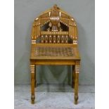 An Egyptian hardwood low set chair with eagle carved back and bergere caned seat on claw feet
