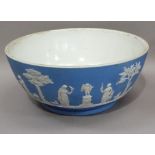 A Wedgwood blue jasper ware punch bowl sprigged with classical figures and cherubs amongst trees, on