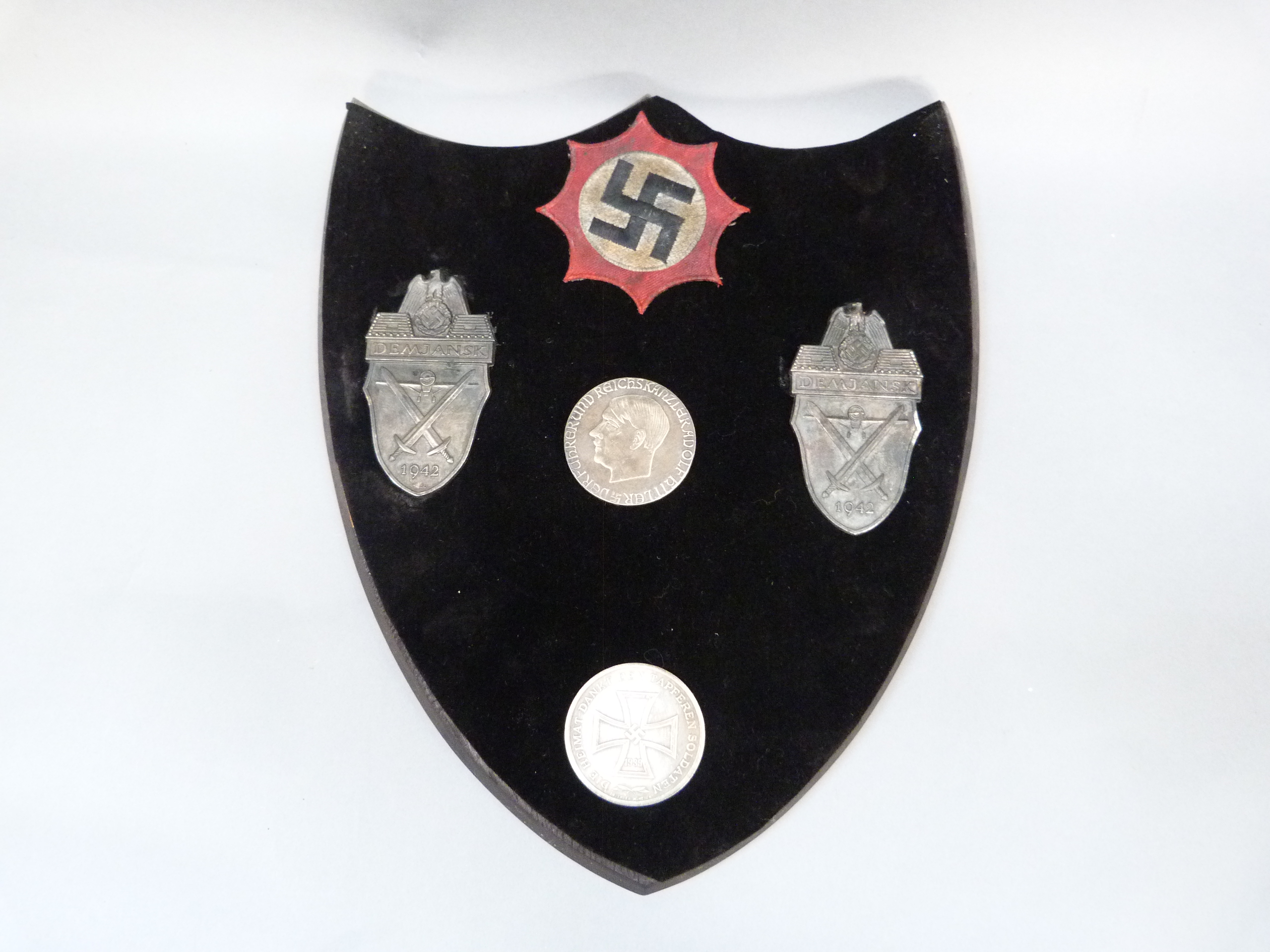 A shield mounted with swastika, two white metal plaques, Dem Jansk 1942, a medallion with portrait