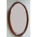 An Edwardian oval wall mirror the bevelled glass within a mahogany frame inlaid with boxwood and