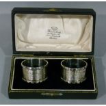 A pair of silver napkins of engine turned decoration with notched rims and vacant cartouche,