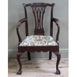 A early 20th century mahogany open armchair of 18th century design having a foliate craved top