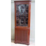 A mahogany standing corner cupboard having a dentil cornice above tracery glazed door and twin