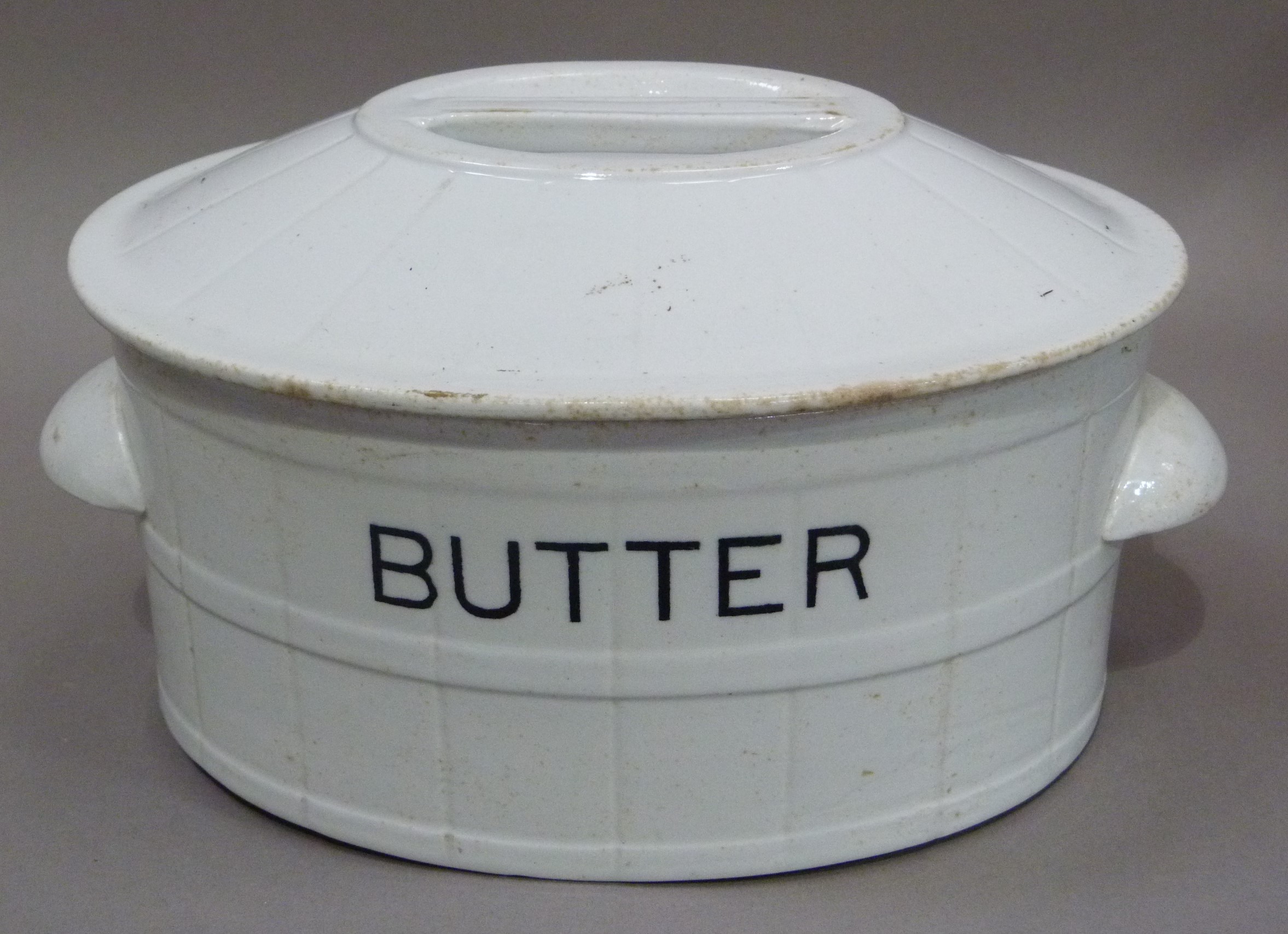 An early 20th century white glazed pottery butter dish the domed top with integral handle,