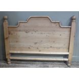 A pine king size bed headboard of arched outline with moulded detail, the uprights with ball