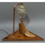 A table lamp the triangular base set with shoe last with copper pipe and pale amber glass shade,