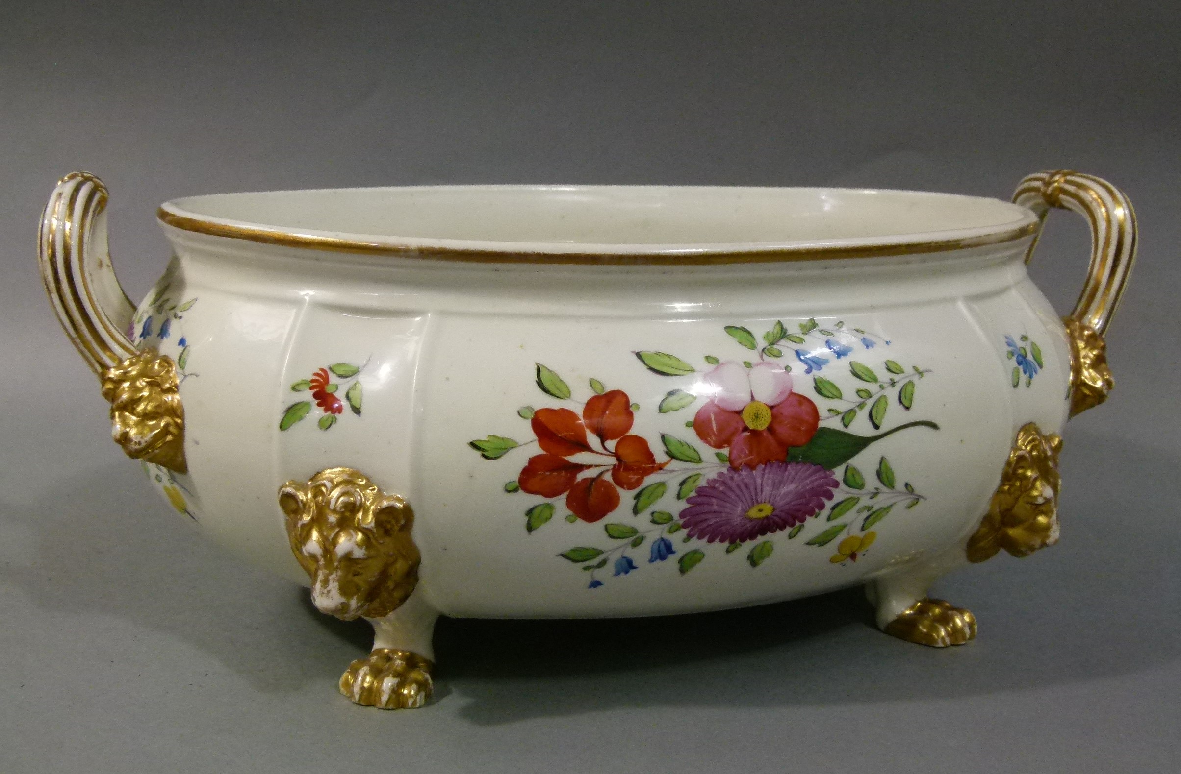 A large two handled porcelain bowl on lion mask and paw feet, polychrome enamelled with sprays of