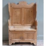 A pine box settle with twin panelled back, winged arms, a lift up box seat and twin panel front