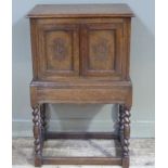 An oak double sided cupboard with hinged rectangular top, the front with panelled lozenge carved