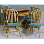 A elm circular extending dining table on quadruple base and six rail back chairs with upholstered