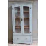 A pale green painted and glazed cabinet having moulded cornice over two glazed doors the interior