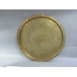 A Far Eastern circular brass tray engraved to the centre with foliate scrolls within a broad