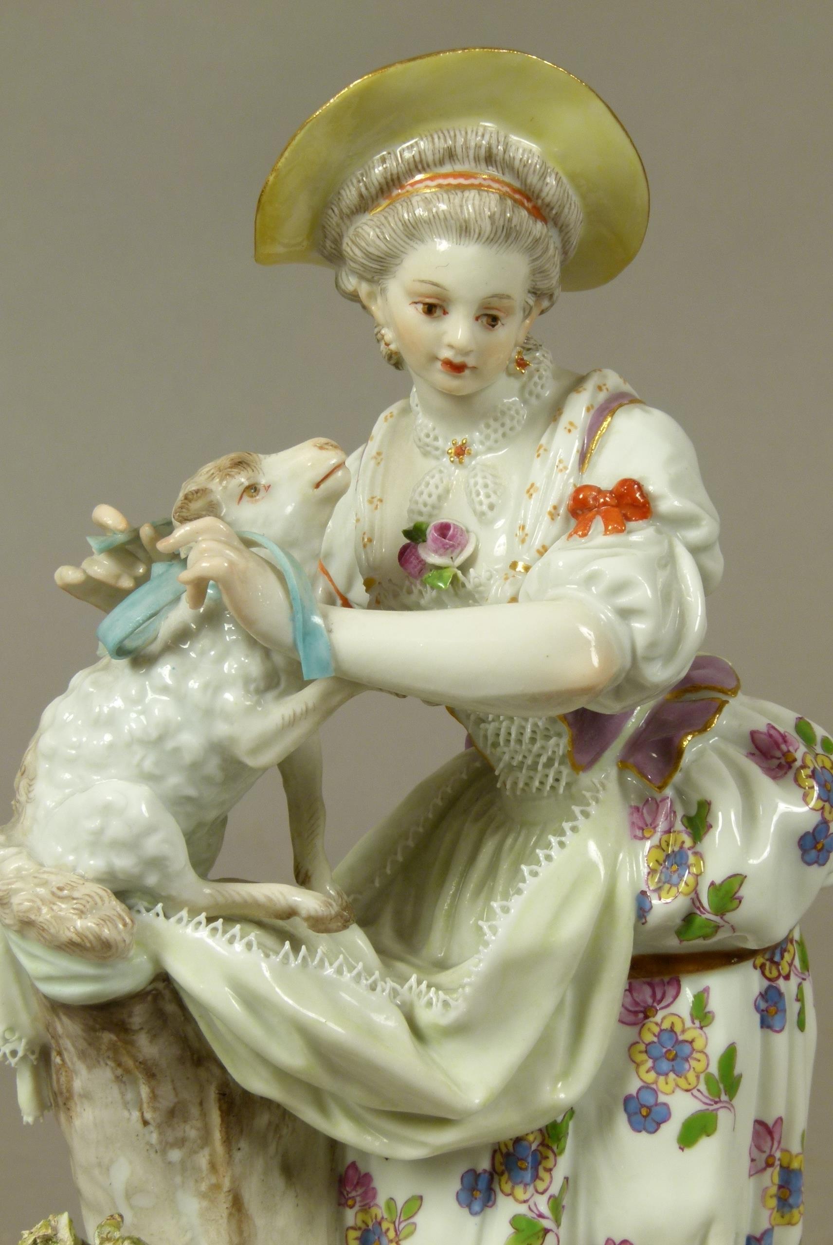 A Meissen figure of a shepherdess, tying a blue ribbon around a lamb's neck, circular base with gilt - Image 2 of 3