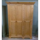 A pine wardrobe enclosed by three twin raised fielded panelled doors, 126cm wide x 190cm high,