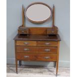 An Edwardian inlaid mahogany dressing table the oval bevel plate on pair of tapered uprights the