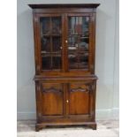 A reproduction cupboard in George II style, the flared cornice above a pair of glazed doors,
