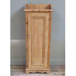 A pine cupboard with three quarter gallery, single panelled door, splayed plinth and bracket feet,