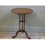 A mahogany pie crust table on three slender ring turned columns and leaf carved cabriole legs with