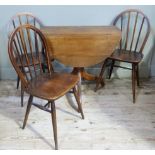 An oak tripod table of oval outline with drop leaves and three Ercol rail back chairs