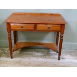 A reproduction pine two drawer side table on turned legs joined by an incurved undertier, 99cm wide