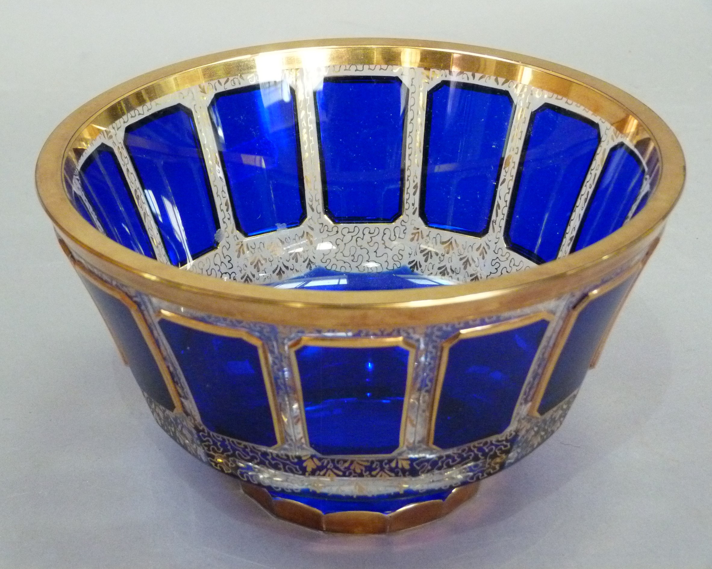 A blue cased clear glass circular pedestal bowl with canted rectangular panelled border on a gilt