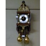 A reproduction 17th century style wall clock with wooden back plate atlas finial three quarter brass