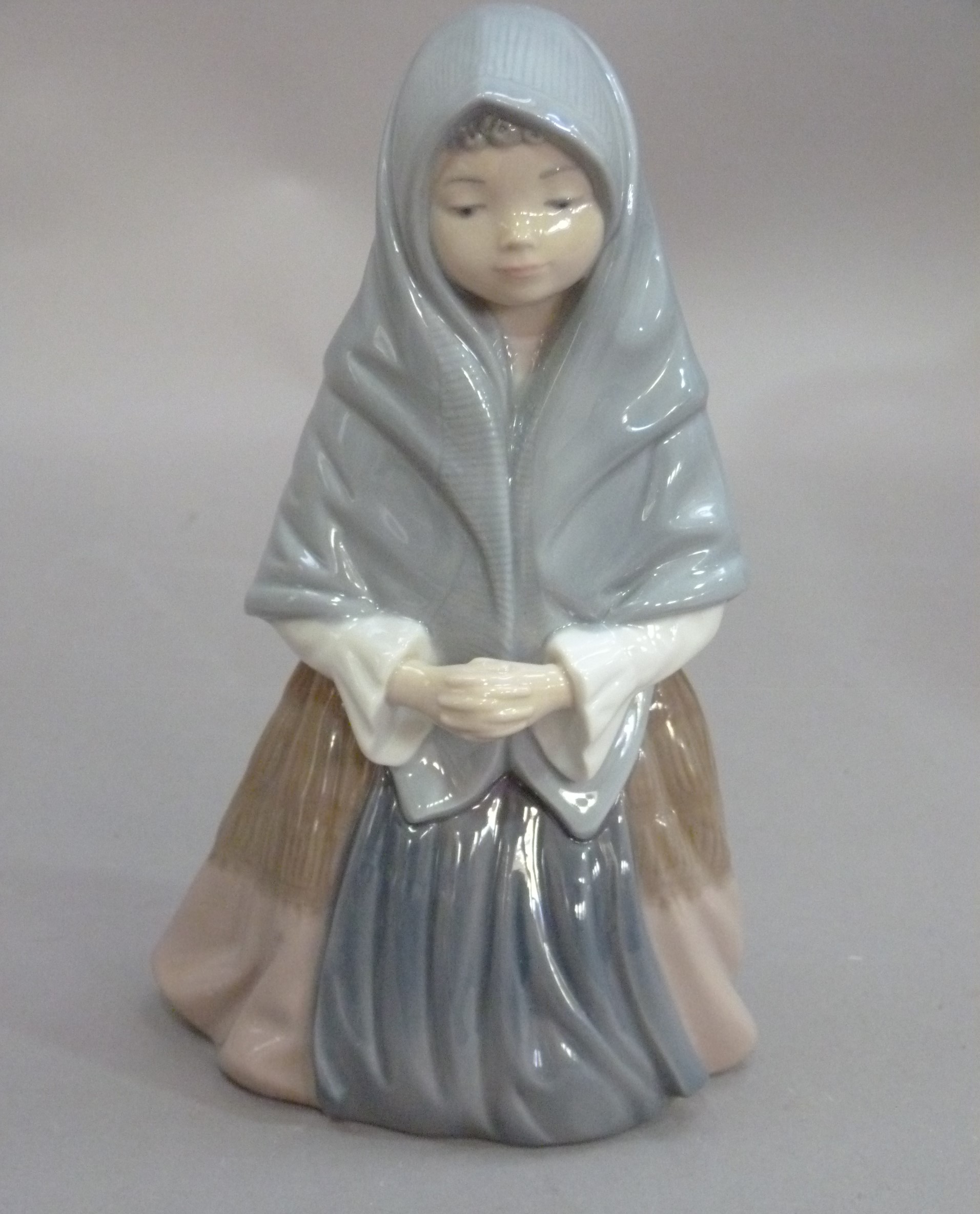 A Nao figure of a kneeling young girl wearing a shawl, 24cm high, printed mark in brown