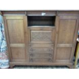 An oak cabinet having a protruding top with angle brackets above an open compartment, drop down