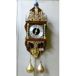 A reproduction 17th century style wall clock with wooden back plate atlas finial three quarter brass