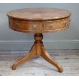 A pale figured walnut drum table with radiating veneer and crossbanding having three drawers and