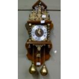 A reproduction 17th century style wall clock with wooden back plate atlas finial three quarter brass