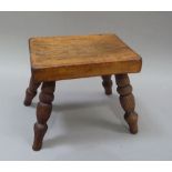 A 19th century small stool the rectangular top above turned elm legs, 23cm wide x 20cm high